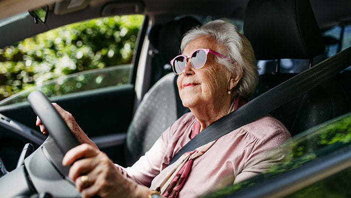 Older senior woman in sunglasses driving a car