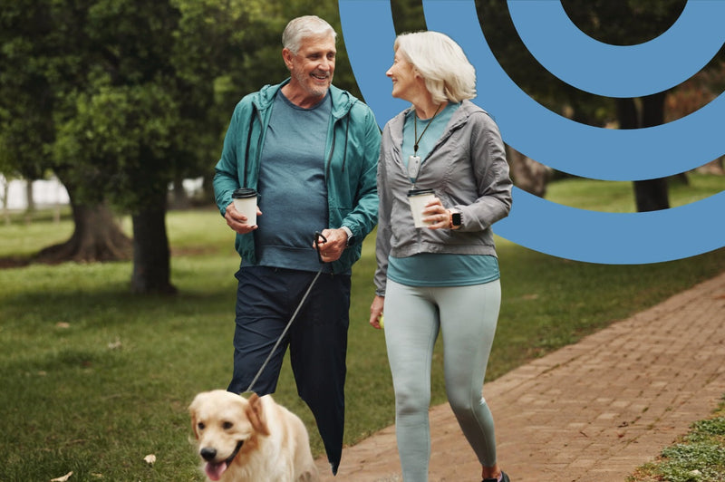 Senior couple walking dog with coffee
