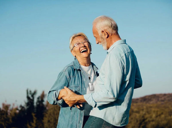 elderly couple dancing, one is wearing a medical alert device